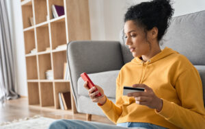 Woman Sitting Against Couch Making Online Payment