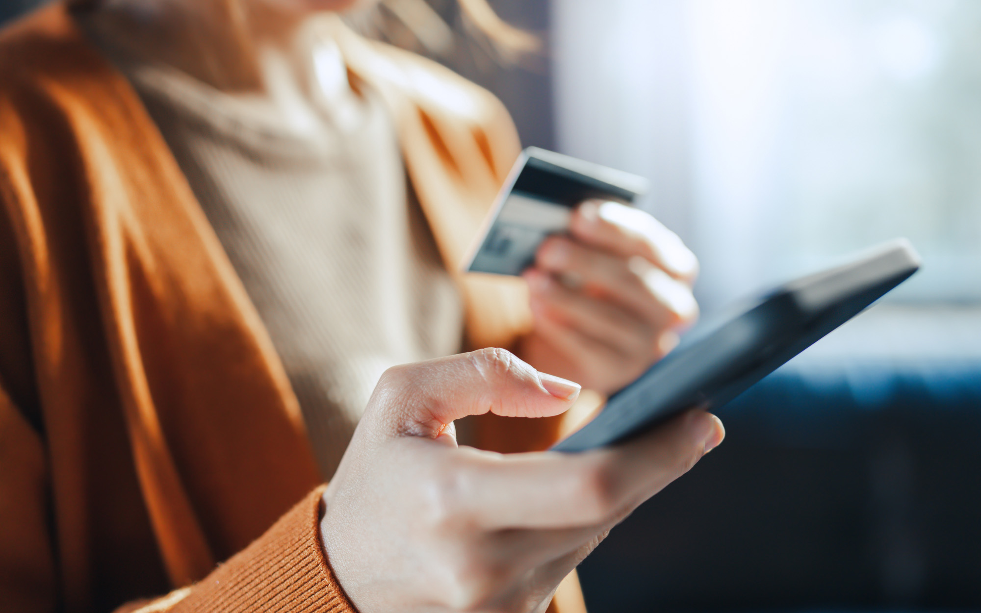 woman holding a credit card and using smart phone for online shopping