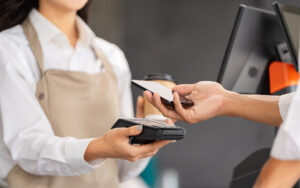 Customer making payment with smartphone at a cafe checkout