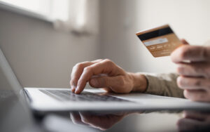 Man hand holding credit card and using laptop at office