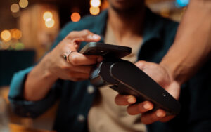 close up of customer paying with cellular device and card machine